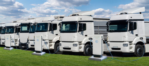 A fleet of electric trucks charging in the daytime against a blue sky