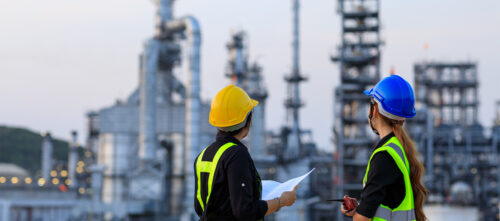 Two engineers stand outside of a chemical industry plant