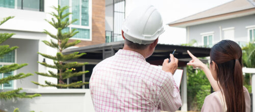 A home owner and contractor stand before a home and discuss a renovation