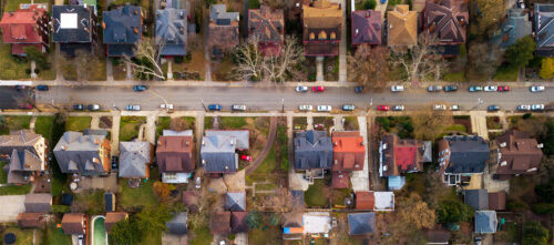 Aerial view of a residential city street in Pittsburgh, with densely packed single family homes and cars parked in driveways and on the street.
