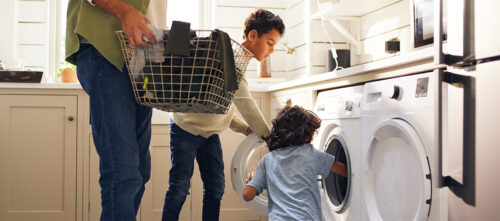 A father and two young boys do laundry