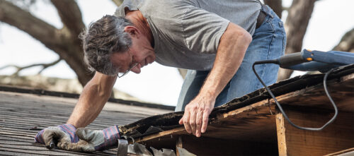 A senior white man repairing his roof.