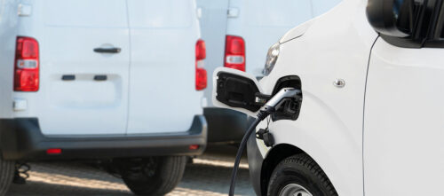 A charging cable connected to a white electric delivery van