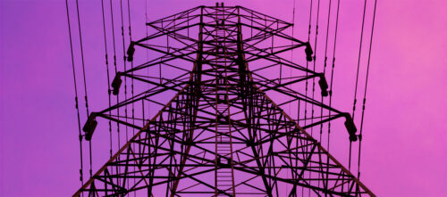 A power line electricity pylon silhouetted against a purple evening sky