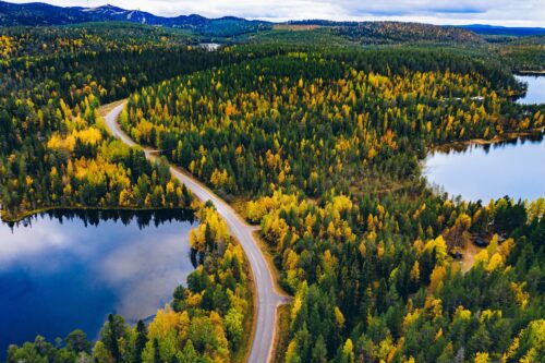 Aerial view of road and colorful autumn forest with mountains and blue lakes in Finland Lapland.