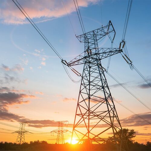 An electricity pylon in front of an orange and blue sky at sunset