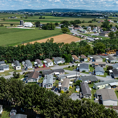 Aerial shot of a rural community, with manufactured homes and a farm in the background