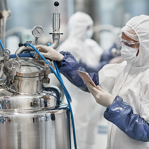 A white, female chemical worker at a chemical manufacturing plant wearing protective gear as she operates equipment