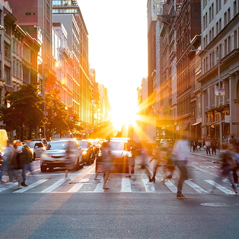 Pedestrians crossing the street at a crosswalk in a lively city intersection.