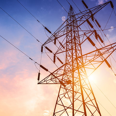 An electricity transmission tower with power lines at sunset