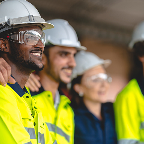 A diverse group of engineers and workers stands together on the jobsite